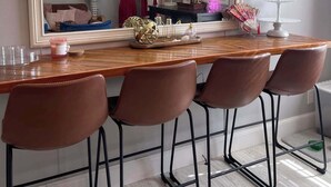 A dining area with a large mirror, a wooden table, four brown chairs, and a small decorative stand. - !!POOL!! PEACEFUL FARMHOUSE IN SHALLOTTE! 
5 MINS TO BEACHES AND OUR SWEET TOWN! (Shallotte)