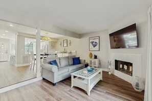 Ein modernes Wohnzimmer mit Sofa, Couchtisch, Kamin und einem an der Wand befestigten Fernseher.