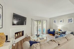 Ein modernes Wohnzimmer mit Kamin, Flachbildfernseher, Sofa und Couchtisch.