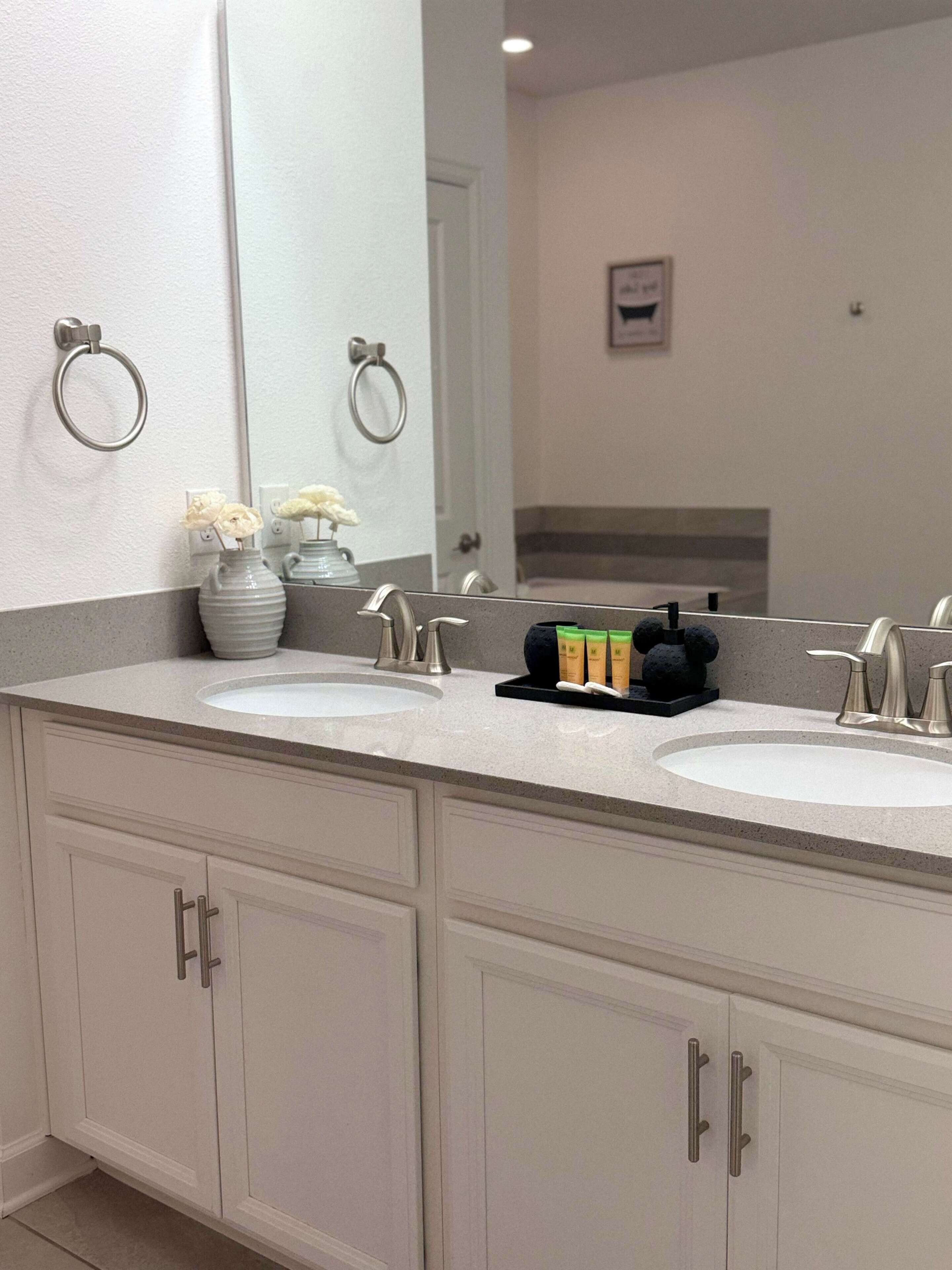 Une salle de bain avec deux lavabos, un grand miroir et un meuble-lavabo avec des placards.