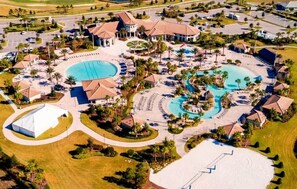 Vue aérienne d’un complexe hôtelier doté de plusieurs piscines, d’une grande tente blanche et d’une plage de sable.