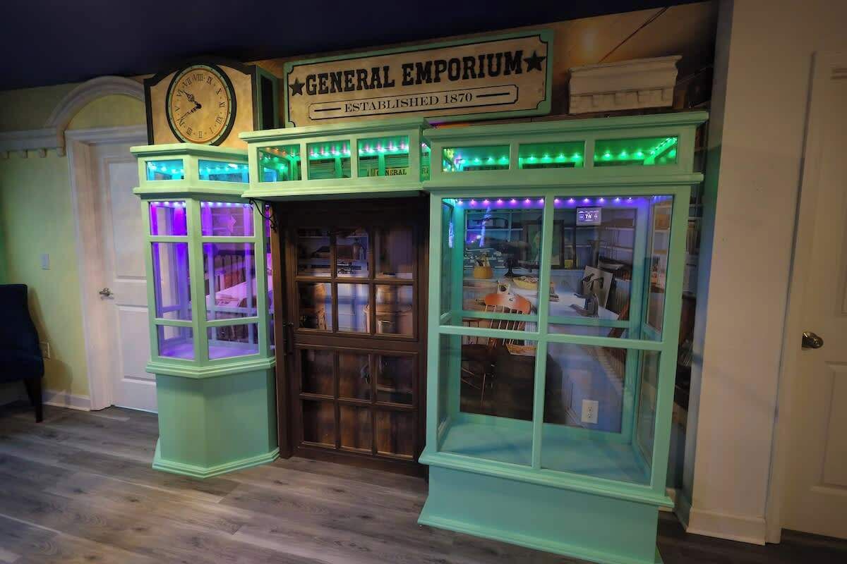 A vintage-themed room with a clock, a sign reading 'General Emporium,' and two display cases with illuminated windows.