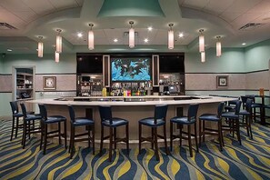 A bar area with a counter, multiple bar stools, and a large screen displaying an underwater scene. - 9BR Fun Villa Sleeps 24 Pool Theater, Themed Near Disney (Four Corners)