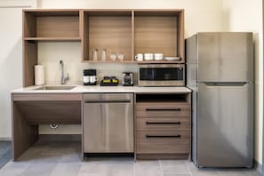 Une cuisine moderne dotée d’appareils électroménagers en acier inoxydable, de meubles de rangement en bois et d’un lave-vaisselle encastré.