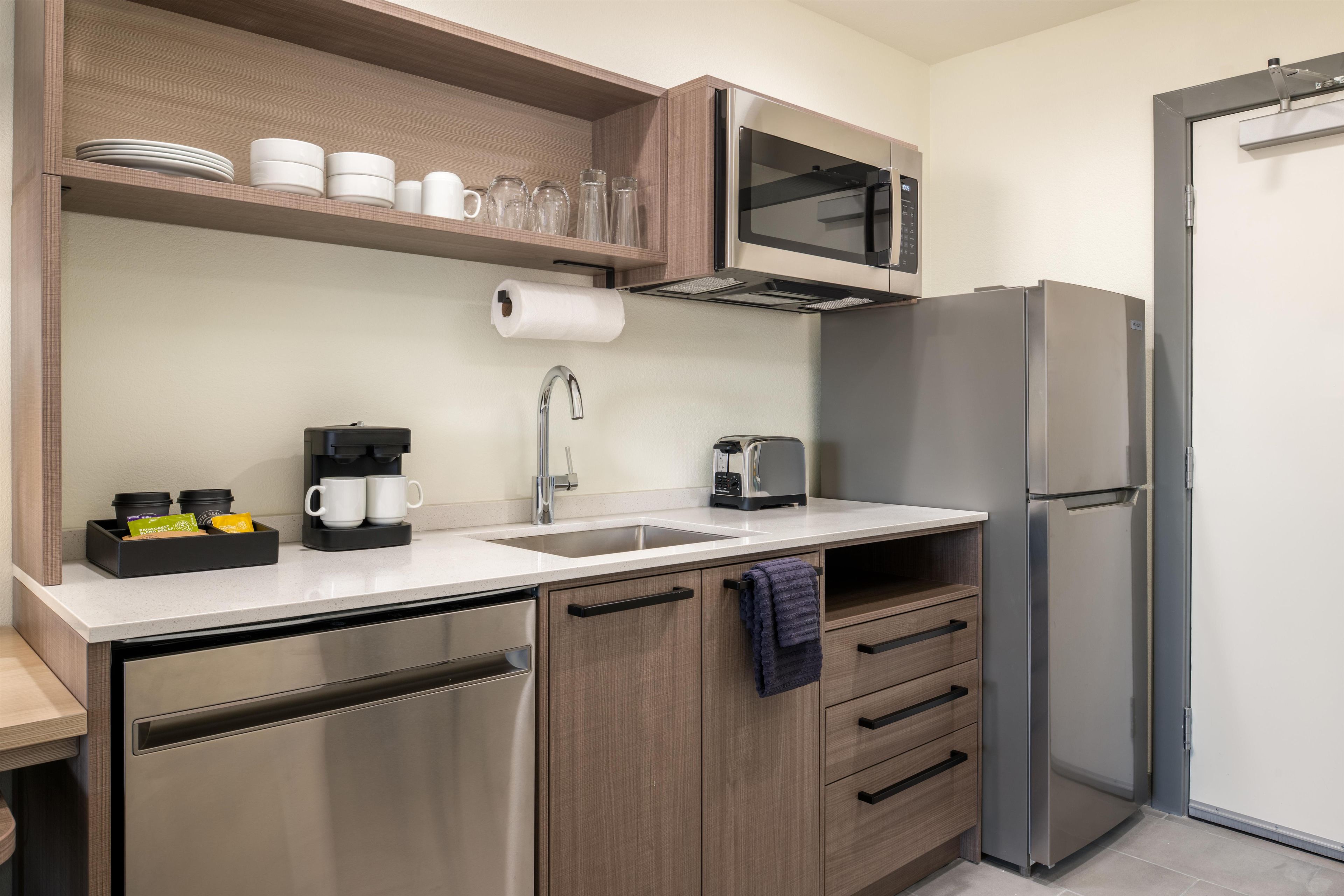 Una cocina moderna con un refrigerador de acero inoxidable, un microondas, una cafetera y un lavabo.