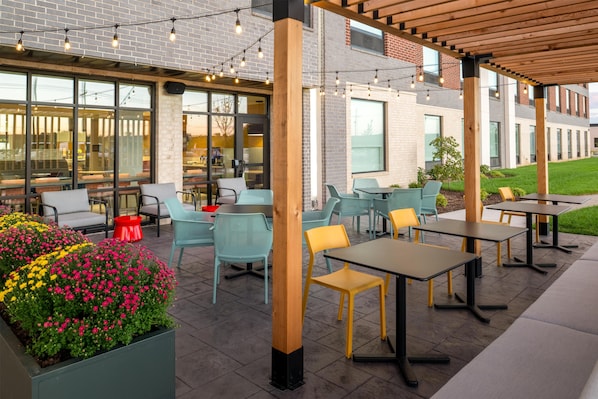 An outdoor patio with seating, a brick wall, and string lights.