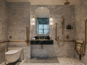 Une salle de bain avec un mur en marbre, un lavabo, des toilettes et un espace douche.