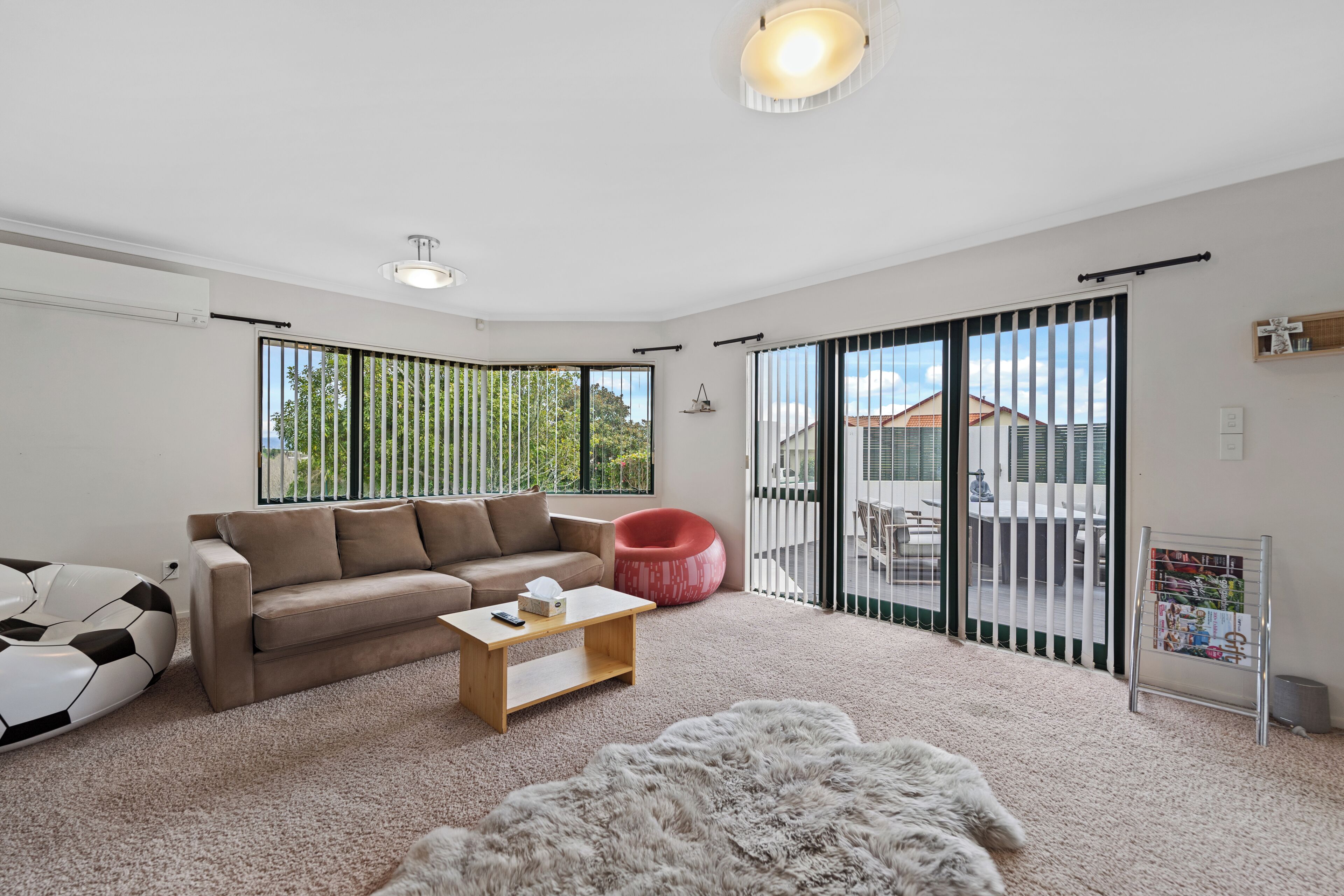 A modern living room with a sofa, a red chair, a coffee table, and a fluffy rug.