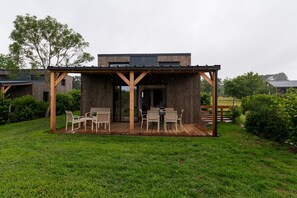 Une terrasse en bois avec des meubles d’extérieur, un espace abrité et une pelouse.