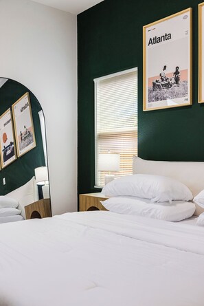 A hotel room with a bed, a nightstand, a mirror, and a window with blinds. - 3BR Modern Home 15 Min to NRG, Downtown & Hobby (Houston)