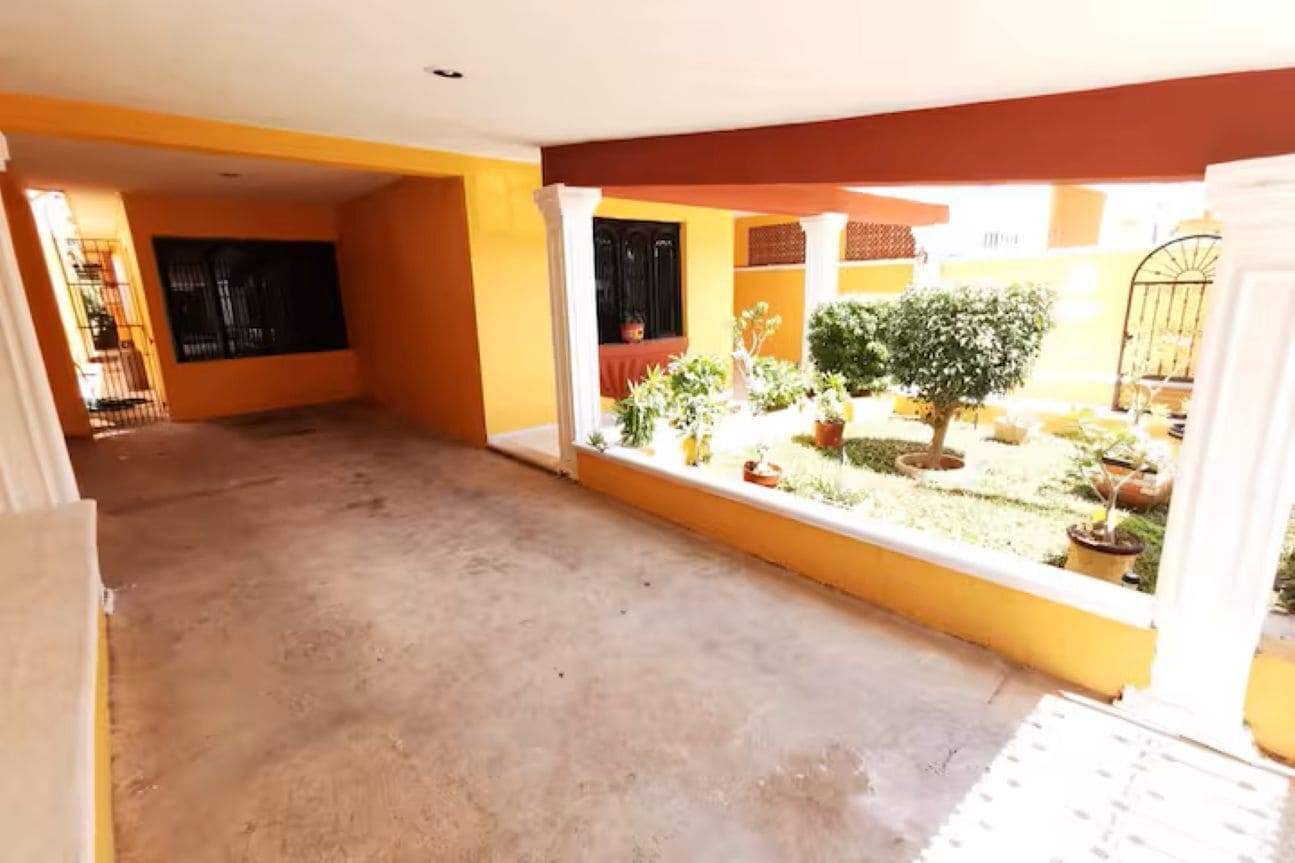 An indoor courtyard with a concrete floor, yellow walls, and potted plants.