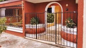 A red brick building with a number '357' on the wall, a gated entrance, and a small porch area with potted plants. - Casa Balfré - Traditional Home in Mérida (Mérida)