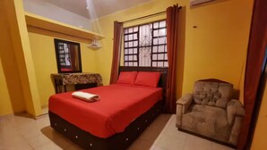A hotel room with a bed, a chair, a small table, and a window with curtains. - Casa Balfré - Traditional Home in Mérida (Mérida)