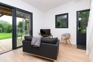 Un salon moderne avec un canapé, un téléviseur et un fauteuil.