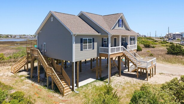 A two-story beach house with a deck and stairs leading to the upper level. - Turtle LIVIN | ICW Views, Sleeps 11, Games & Relax (North Topsail Beach)