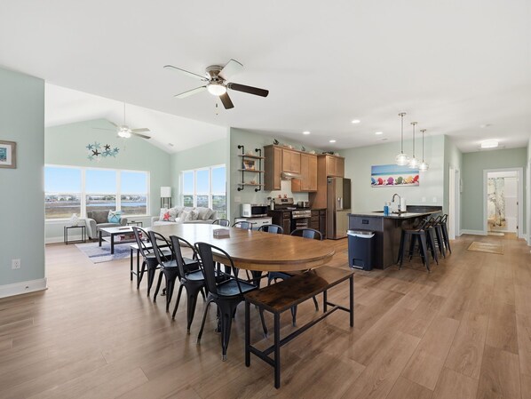 Una cocina amplia con comedor, ventanas grandes y ventilador de techo.