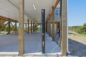 A covered outdoor area with wooden beams, a concrete floor, and a black pole with a hose.