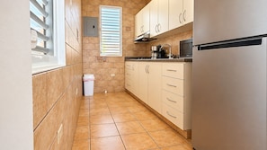 A kitchen with beige cabinets, a stainless steel refrigerator, and a window with blinds. - 2-story villa with ocean views, hot tub, 180° ocean views, and sunsets – sleeps 8   (Aguada)
