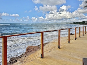 A wooden boardwalk along a rocky coastline with waves crashing onto the shore. - Oceanfront 2-Story Villa with Hot Tub, 180° Ocean Views, and Sunsets – Sleeps 8 (Aguada)
