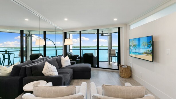 A modern living room with a large sofa, armchairs, and a television. - Luxury Waterfront 2BR/2BA Marco Island condo (Marco Island)