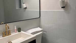 A bathroom with a white sink, a mirror with a black frame, a toilet, and a towel rack.