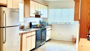 A kitchen with a refrigerator, stove, microwave, and wooden cabinets.