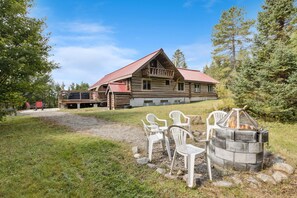 Een lodge met houten gevel, buitenterras en vuurkorf.