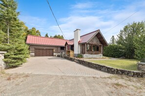 Een chalet met een rood dak, stenen muren en een verharde oprit.