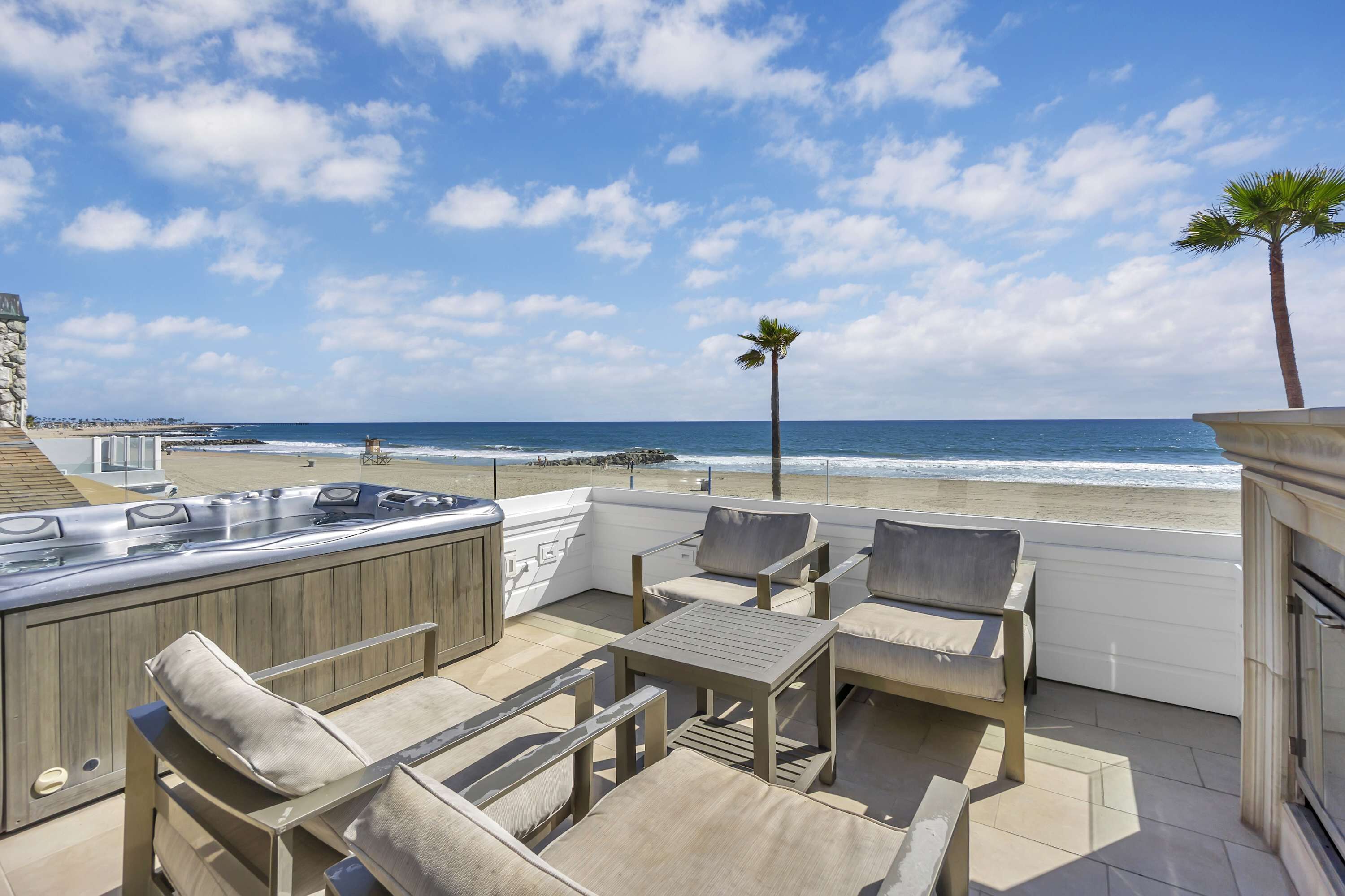 A patio with outdoor seating, a hot tub, and a view of the beach.