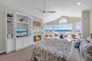 A bedroom with a TV, fireplace, and a balcony with a view of the beach. - Beachfront Oasis: Rooftop and Firepit, Sleep 12 (Newport Beach)
