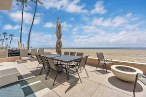 A patio with a table and chairs, a fire pit, and a pool. - 4207 Seashore Beachfront Oasis Rooftop and Firepit, Sleep 12 (Newport Beach)