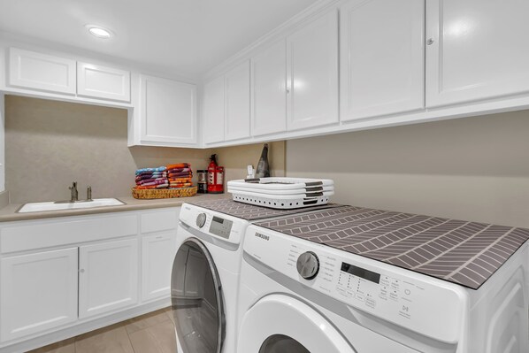 Un espace buanderie comprenant un lave-linge, des paniers à linge empilés et un évier.