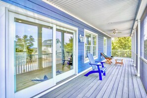 A covered porch with a wooden deck, large sliding glass doors, and outdoor seating. - "The Haven of Rest" – Multi-Gen Luxury Beach House w/ Elevator & Rooftop Views! (Milton)