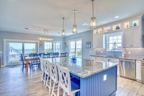 A spacious kitchen with a large island, pendant lighting, and a view to the outside. - "The Haven of Rest" – Multi-Gen Luxury Beach House w/ Elevator & Rooftop Views! (Milton)
