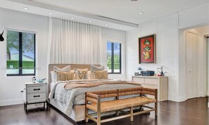 A modern bedroom with a large bed, bedside tables, a bench, and a painting. - Palm paradise (Miami)