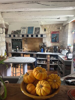 A kitchen with a brick oven, a dining table, and a bowl of pumpkins. - Beautiful country house 3 km from Angoulême (Soyaux)