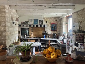 A rustic kitchen with exposed brick walls, a vintage-style stove, and a variety of kitchen utensils. - Beautiful country house 3 km from Angoulême (Soyaux)
