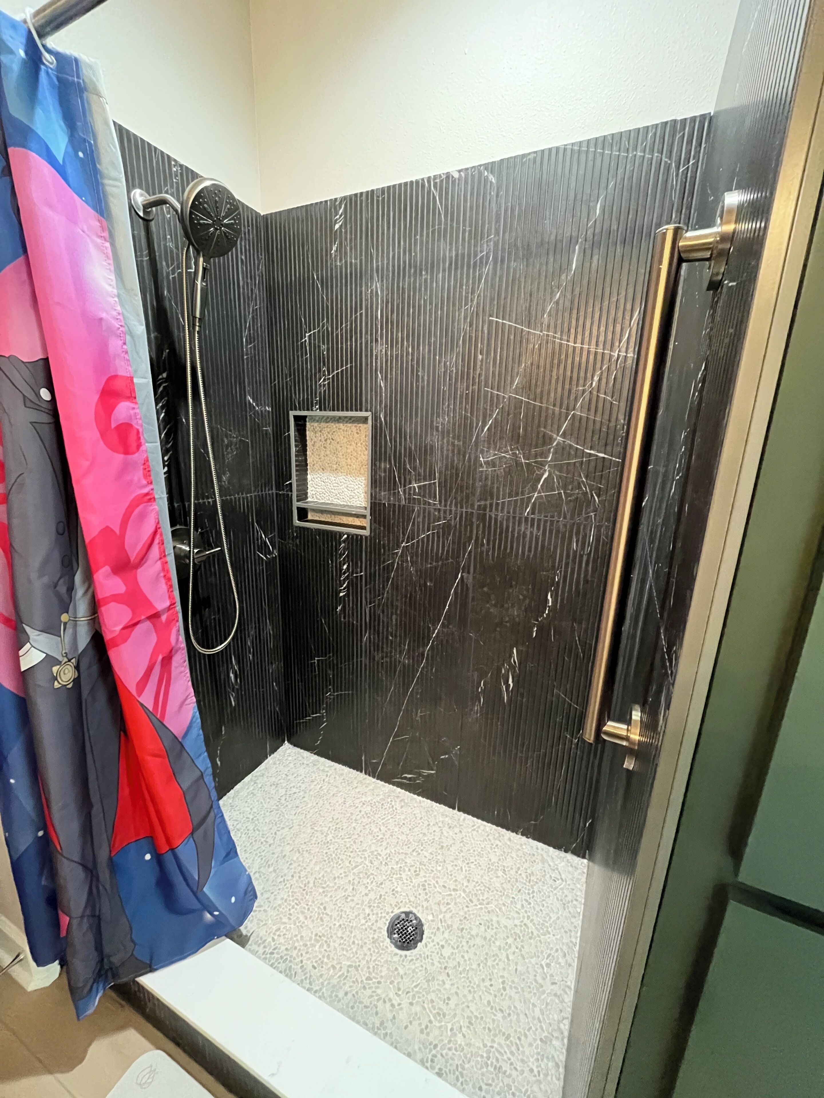 A shower stall with a glass door, a showerhead, and a small window.