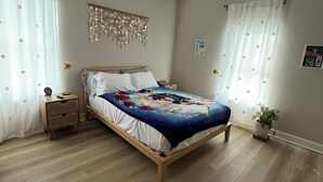 Ein Schlafzimmer mit einem hölzernen Bett, einem Deckenventilator, einem Nachttisch und einer Topfpflanze.