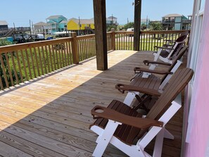 A wooden deck with outdoor seating. - Cozy Anime Beach House - Quick Walk to Beach (Bolivar Peninsula)