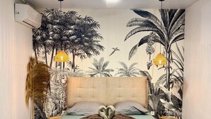 Ein Schlafzimmer mit einem Bett, einem Deckenventilator, Wandgemälde und einem Nachttisch.