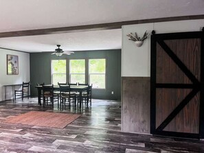 Un espace repas comprenant une table et des chaises, un ventilateur de plafond et une grande porte en bois de style grange.