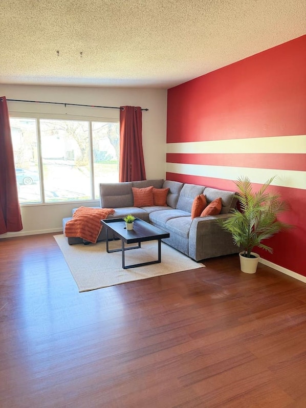 A living room with a sectional sofa, a coffee table, and a potted plant.