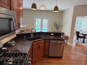 A kitchen with wooden cabinets, a stainless steel refrigerator, a double sink, and a dishwasher. - The Fairways Clubhouse - Heated Pool + Saratoga Track Season + Golf (Gansevoort)