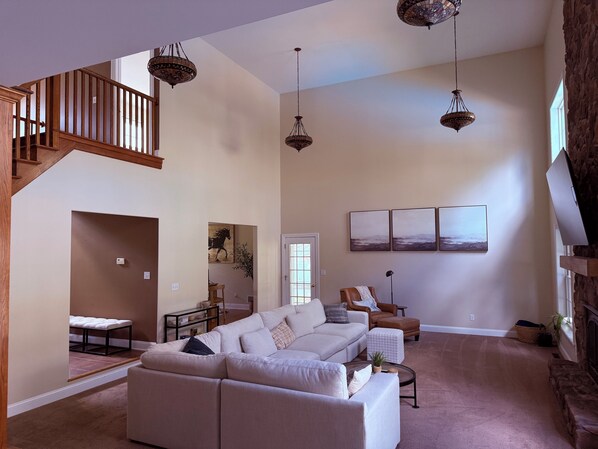 A spacious living room with a large sectional sofa, a fireplace, and a staircase.