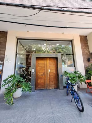 A building entrance with a wooden door, potted plants, and a bicycle. - Charming Providencia Apartment, 1min from subway, close to costanera center, parking (Providencia)