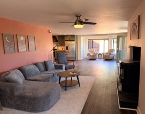 Ein Wohnzimmer mit Ecksofa, Couchtisch, Fernseher und Deckenventilator.