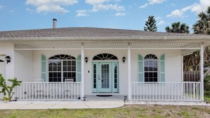 Une maison de plain-pied avec un porche, une porte d’entrée et deux fenêtres équipées de volets.