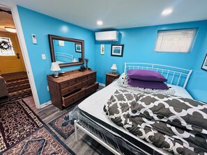 Ein Schlafzimmer mit Bett, Kommode, Spiegel und Wandklimaanlage.