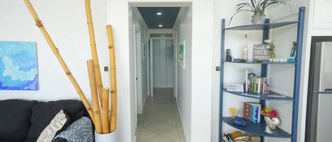 Un passadís amb una porta blanca, una estanteria blava i un sofà negre.